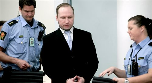 Anders Behring Breivik w asyście norweskich policjantów podczas swojego procesu w maju 2012 r.