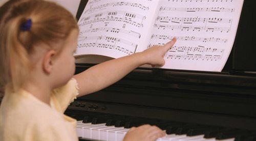 Dziecko uczy się grać na pianinie