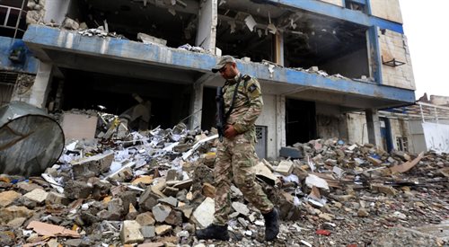 Iracki żołnierz przechodzi obok ruin budynku, w którym islamiści z ISIS urządzili więzienie