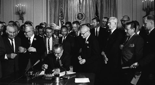 Prezydent USA Lyndon B. Johnson podpisuje ustawę o swobodach obywatelskich dla Afroamerykanów, za plecami prezydenta Martin Luther King (2 lipca 1964), aut. Cecil Stoughton, źr. Biały Dom, Wikipediadp