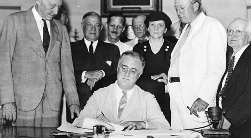 Prezydent Franklin Roosevelt podpisuje Ustawę o Ubezpieczeniach społecznych, jedną z ustaw Nowego Ładu  w otoczeniu senatorów i kongresmenów, 14 sierpnia 1935 źr. Biblioteka Kongresu Stanów Zjednoczonych Wikimedia Commonsdp