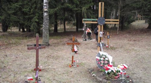 Metalowy Krzyż Polski w otoczeniu kilku mniejszych krzyży, mających imiennie upamiętniać Polaków, którzy mogli być rozstrzelani w Kuropatach