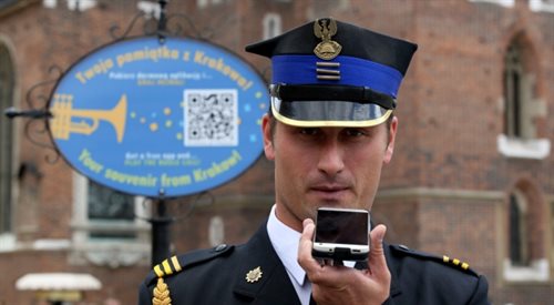 Krakowski hejnalista Michał Kołton prezentuje działanie nowej aplikacji mobilnej na smartfony dla turystów na Rynku Głównym w Krakowie
