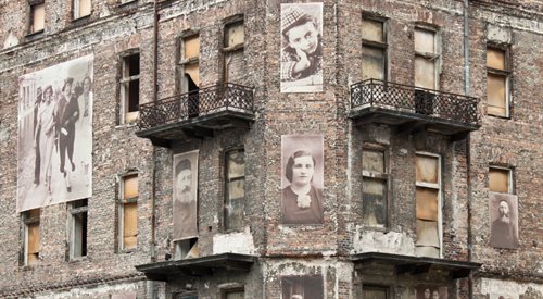 Twarze żydowskich mieszkańców umieszczone na ścianie budynku znajdującego się na terenie getta warszawskiego