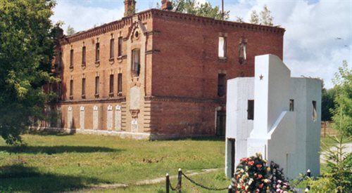 Radziecki pomnik postawiony na miejscu dawnego obozu w 1962. W tle ruiny budynku obozowej administracji