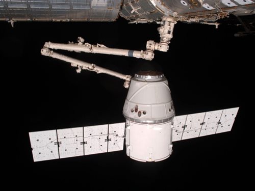 Automatyczne ramię stacji kosmicznej pomaga przemieścić kapsułę Dragon we właściwe miejsce, fot. NASA (maj 2012)