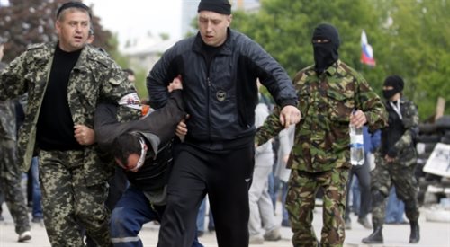 Prorosyjscy bojownicy w Doniecku, prowadzą niezidentyfikowanego mężczyznę, najprawdopodobniej zakładnika