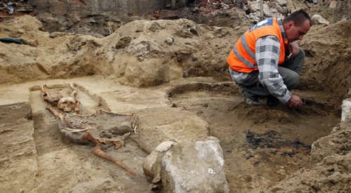 Archeolog Łukasz Obtułowicz przy pracy na budowie Drogowej Trasy Średnicowej w Gliwicach, obok szczątków ciał z odjętymi głowami
