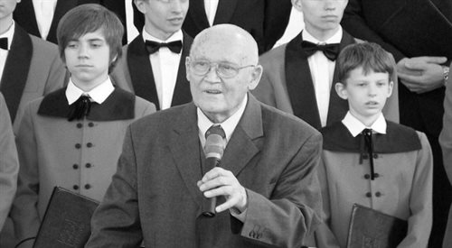 Stefan Stuligrosz na tle chóru Poznańskie Słowiki podczas koncertu w kościele Najświętszego Serca Jezusa w Śremie.
