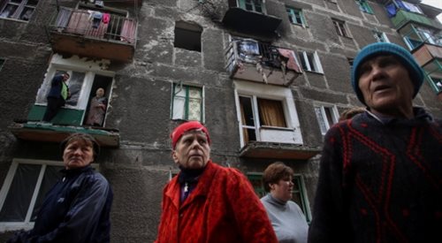 Mieszkańcy ukraińskiego Debalcewa. W tle ostrzelany budynek mieszkalny